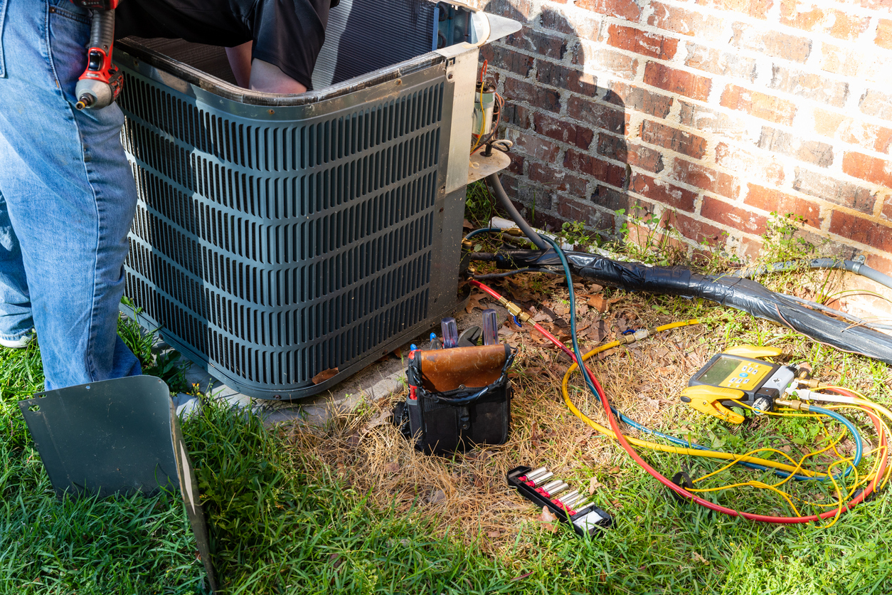 HVAC technician performing a maintenance service on an outdoor AC unit