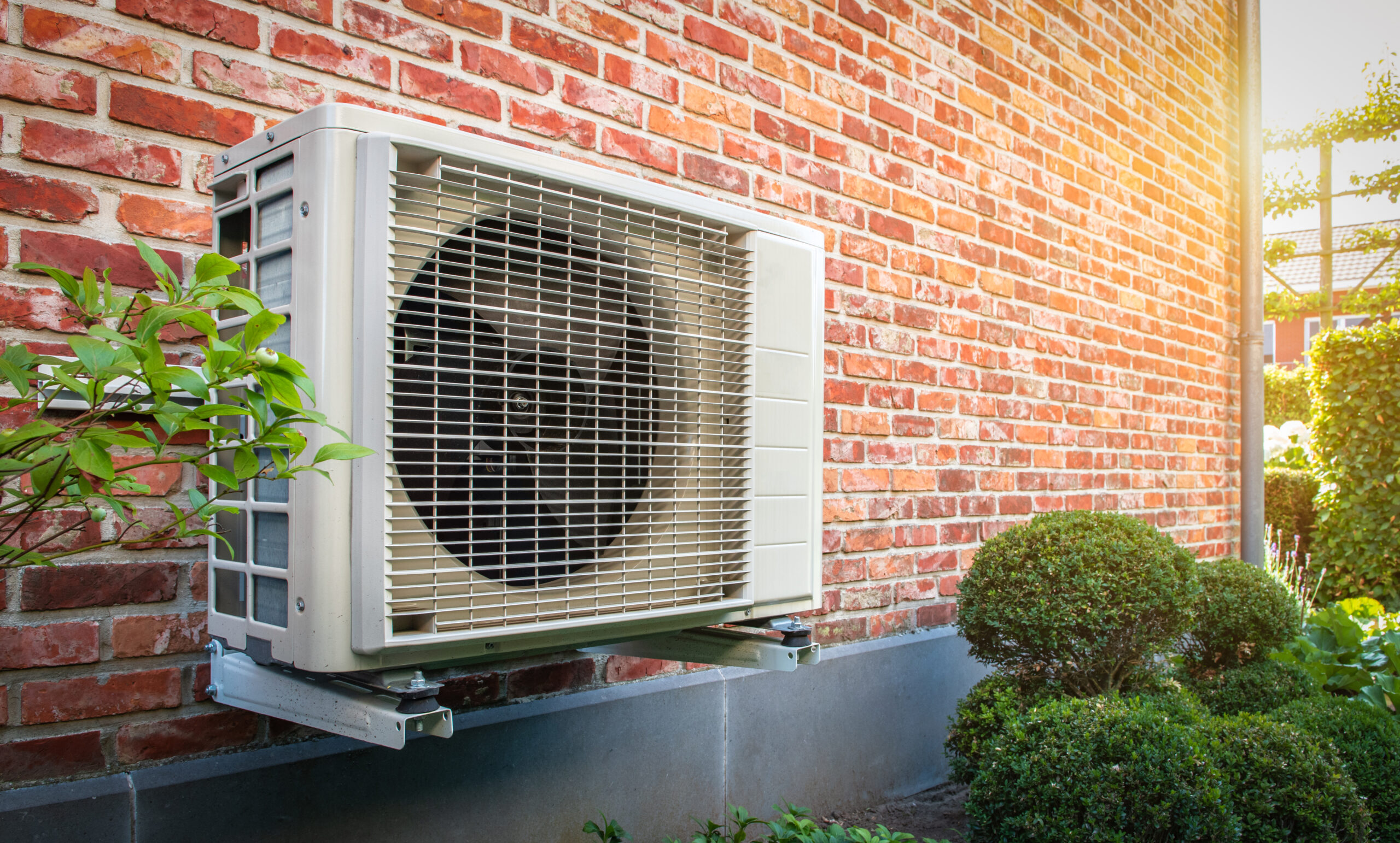 Heat pump mounted to the brick wall of a home