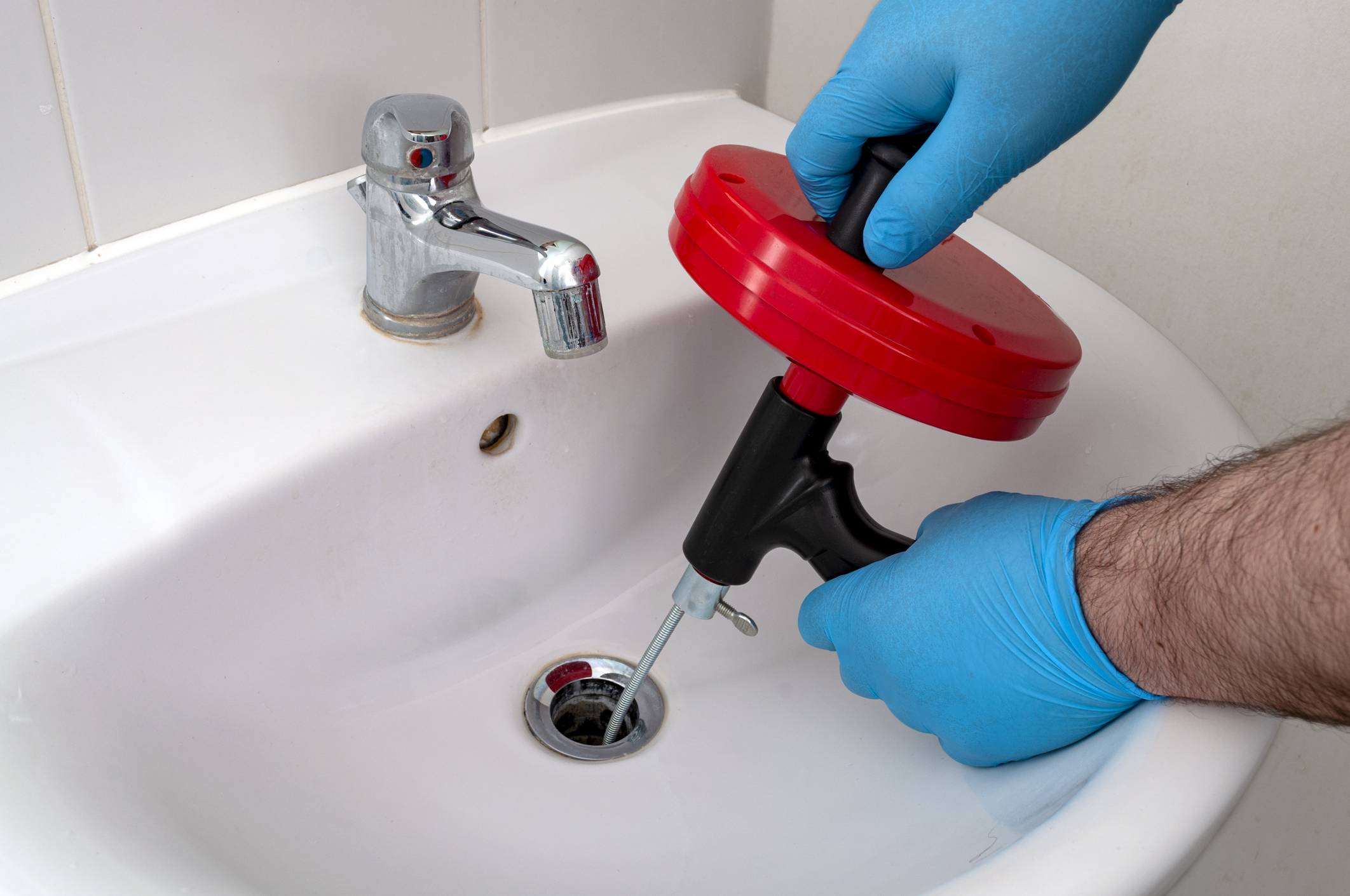 A plumber using a drain snake to clean out drains