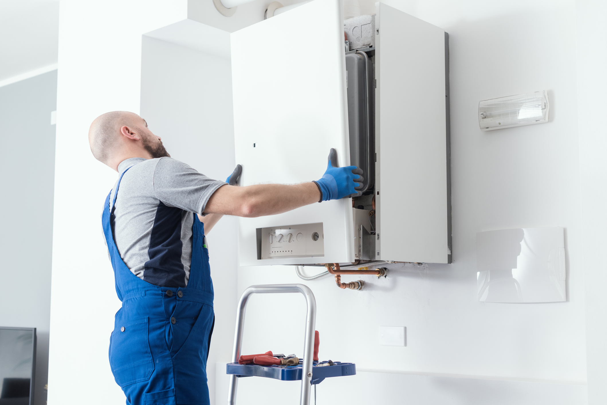 HVAC technician replacing the cover of a boiler after installation