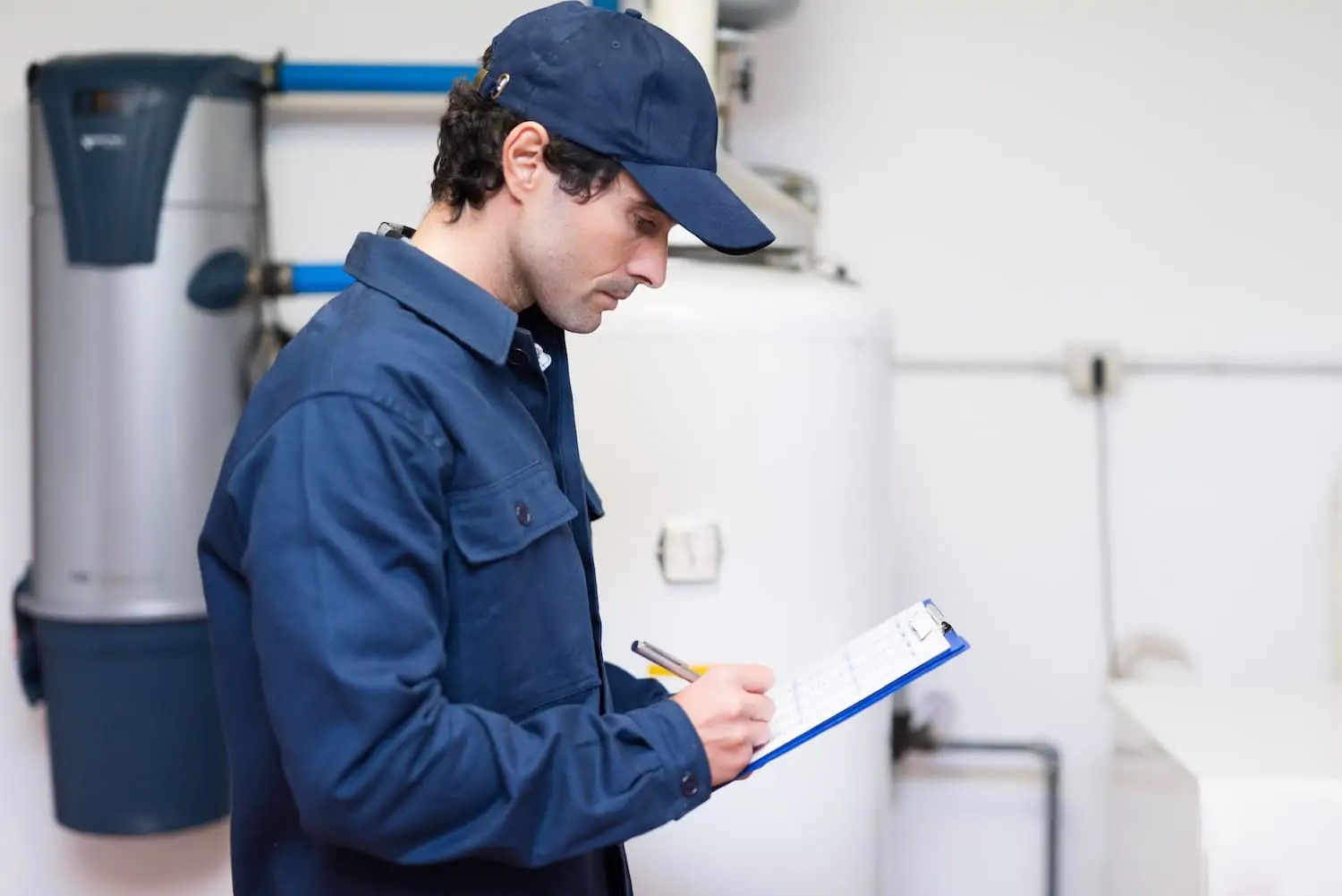 Plumber with clipboard in front of residential water heaters