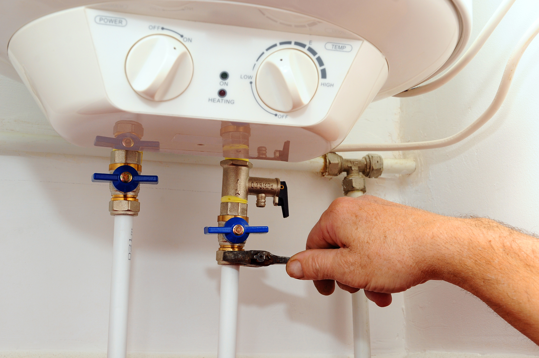 Plumber’s hand fixing the pipe of a tankless water heater